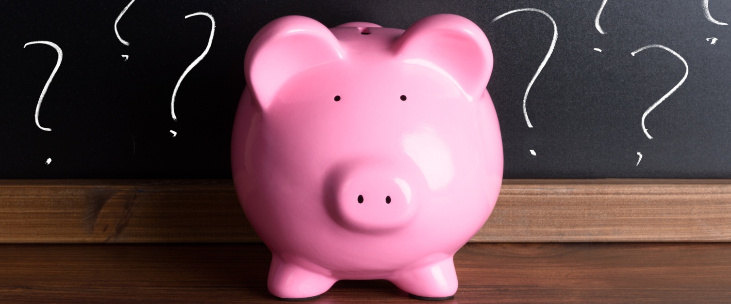A pink piggy bank in front of blackboard with question marks.