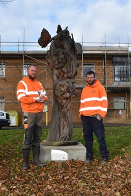 Image shows two men standing next to a sculpture