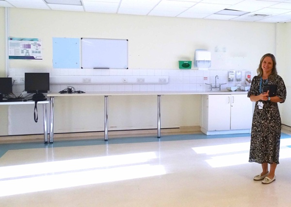 Image shows a person standing in a large empty room.