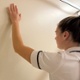 Image shows a physiotherapist with her left arm on the wall.