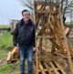 Image shows a man standing next to some wooden pallets