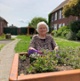 Image shows a woman sat behind a flower bed