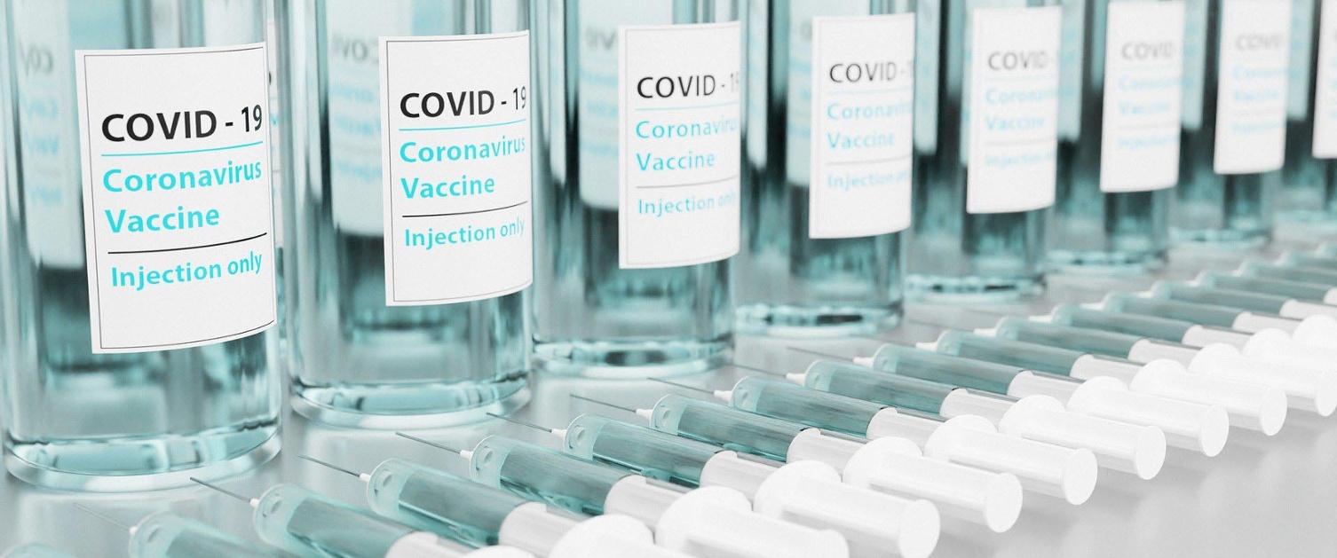 Covid vaccine bottles lined up side by side next to syringes