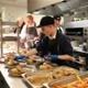 Children placing food on a plate in a kitchen