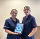 Karly holding an iPad displaying the app stood next to Catrin
