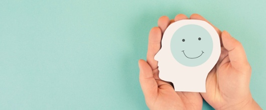 Hands holding a picture of a head with a smiling face