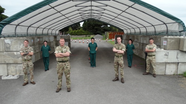 Four soliders are pictured standing socially distanced with three health care support workers.