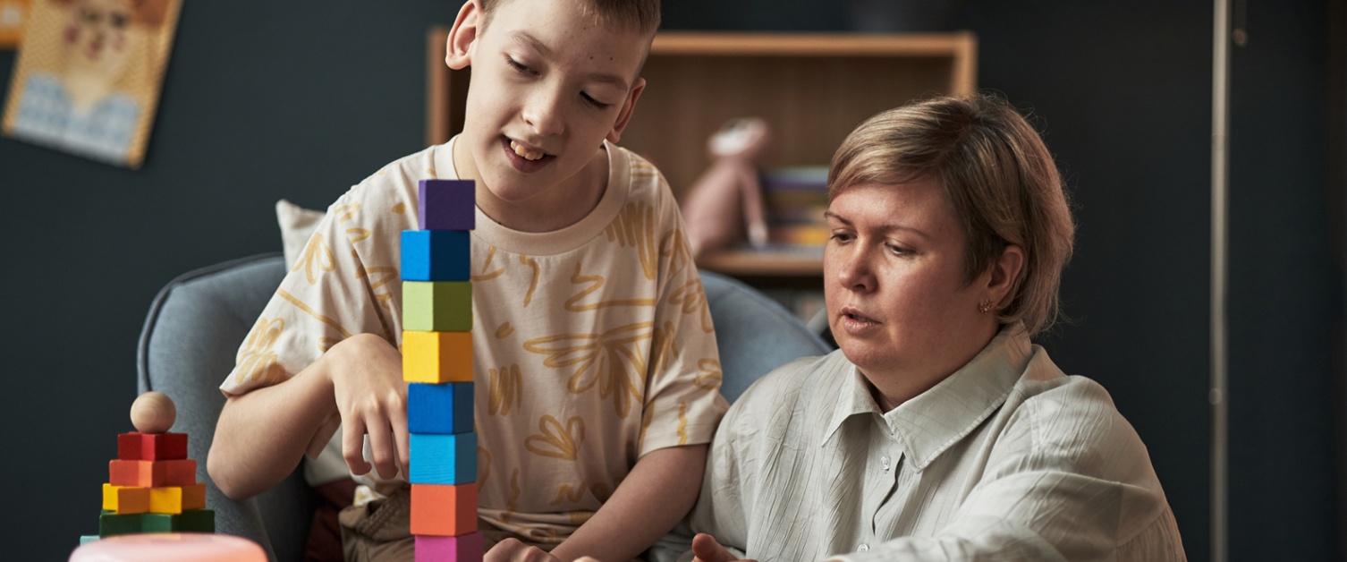 A young boy with additional needs stacks coloured blocks