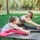 A woman and a young girl doing yoga in a field 