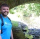 Image shows a man standing by a canal bridge.