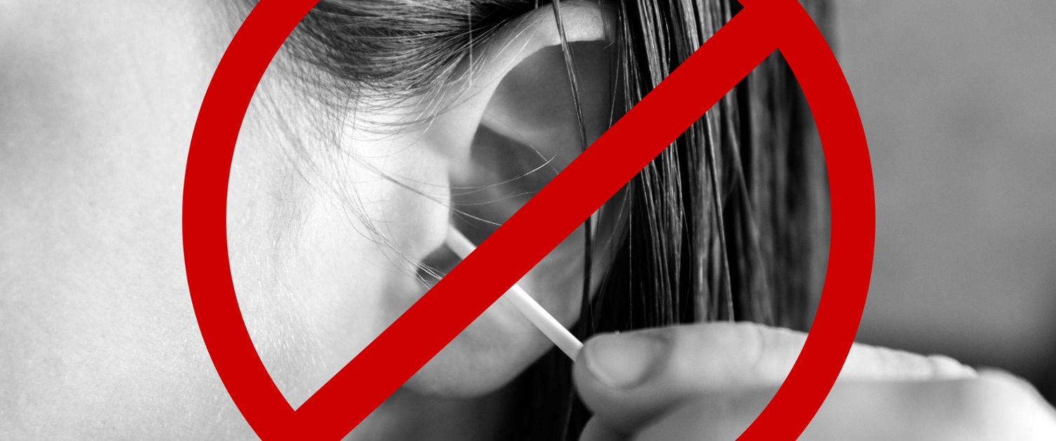 A person cleaning their ear with a cotton bud and a red line through it.