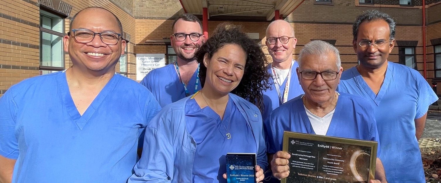 Image shows cardiac staff in scrubs, holding the award