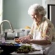 An image of an elderly woman doing the washing up