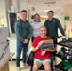 Image shows a group of people standing around a man in a wheelchair