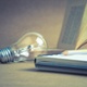 An image of a lightbulb next to a notebook.