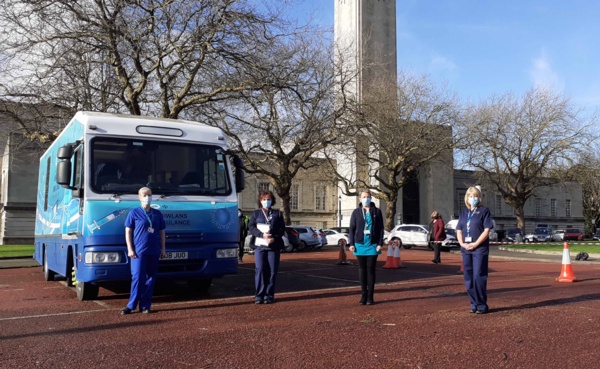 Four nursing staff stand outside the Immbulance parked at Guildhall.