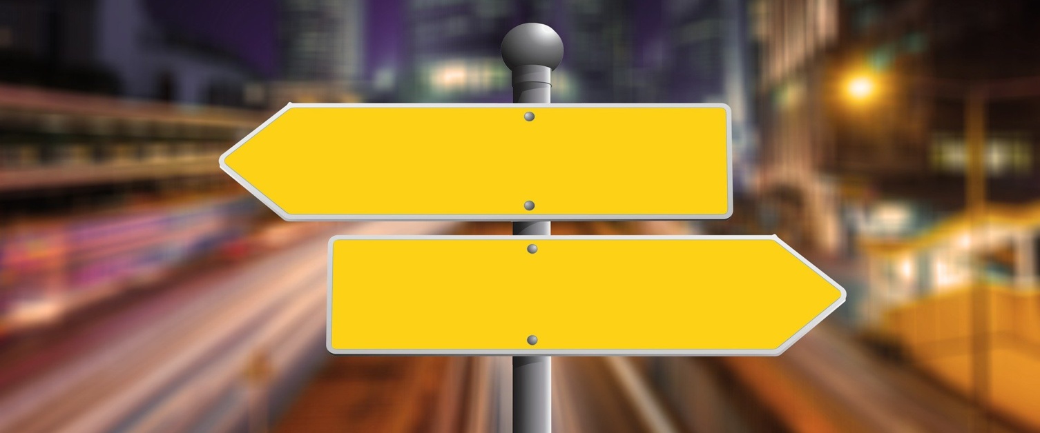 Image shows two blank yellow direction signs pointing in opposite directions.