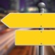 Image shows two blank yellow direction signs pointing in opposite directions.