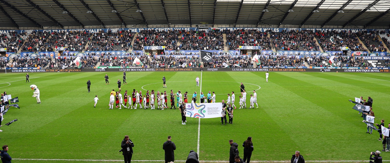 Footballers on a pitch with a big banner in front of them reading 