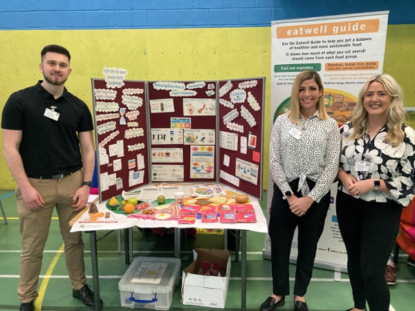 A man and two women stood next to a healthy eating display