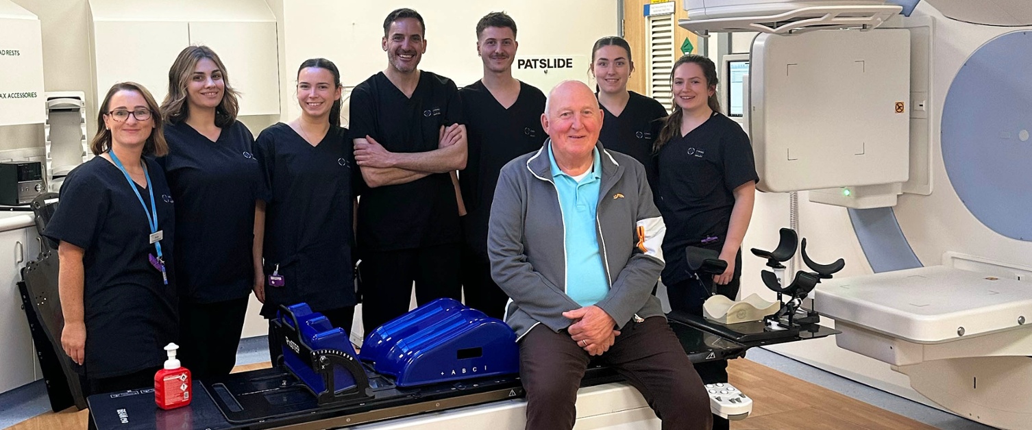 Image shows staff and a patient in a radiotherapy department.