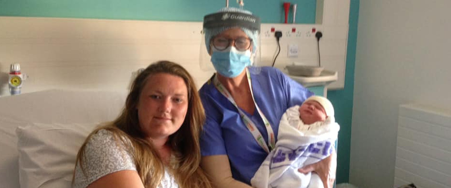 Image shows Lucy Jones lying on the sofa with baby in her arms.