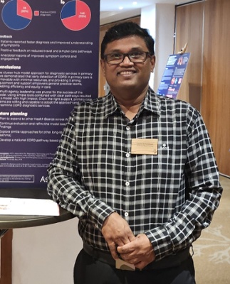 Image shows a man standing in front of a sign