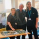 Senior radiographer Tracy Lewis stands with patient Michael Puffett and radiographer Rebecca Lloyd next to the puzzle table.
