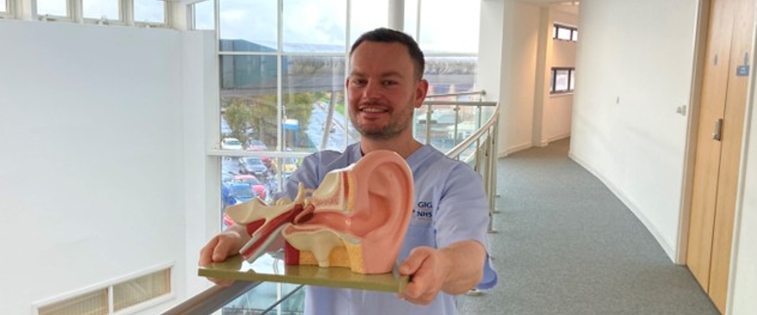 Image shows man holding a 3D ear diagram.