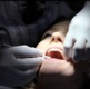 A woman with her mouth open is examined by a dentist.