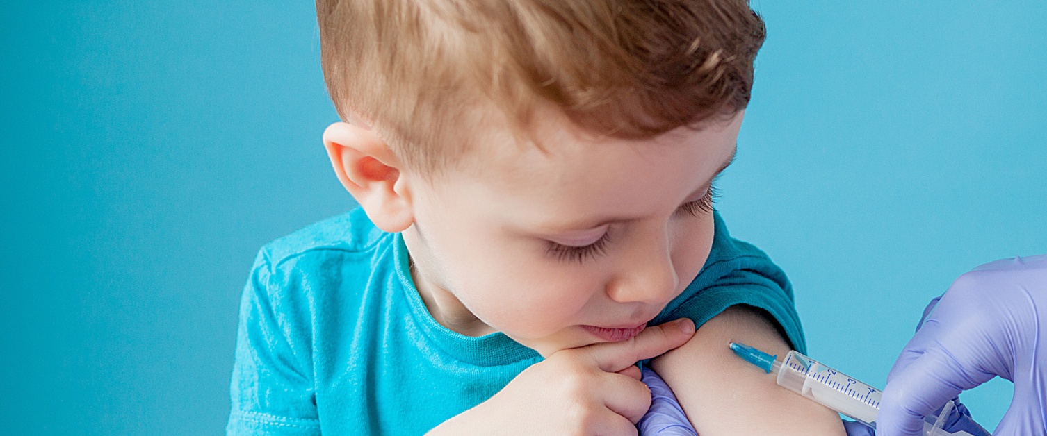 A small boy with sleeve rolled up gets an injection in his arm.