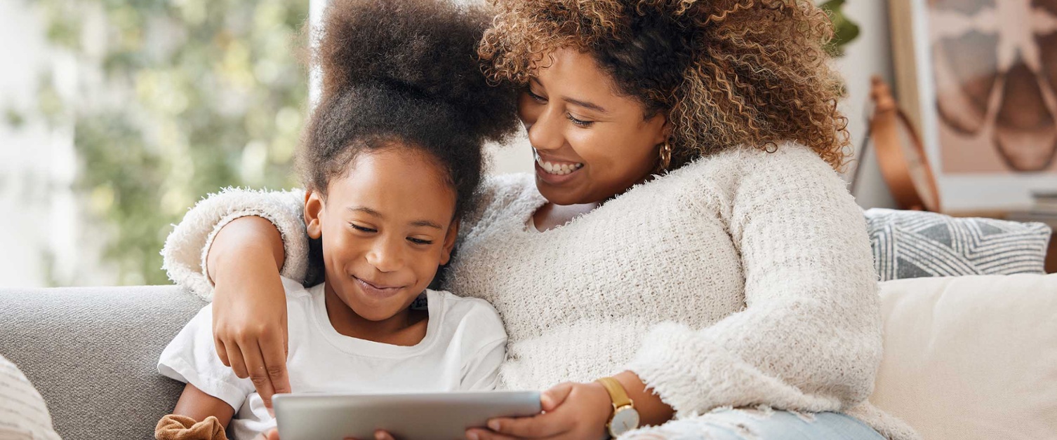 Image shows mum and young daughter looking at tablet computer together.