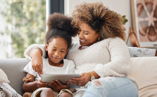 Image shows mum and young daughter looking at tablet computer together.