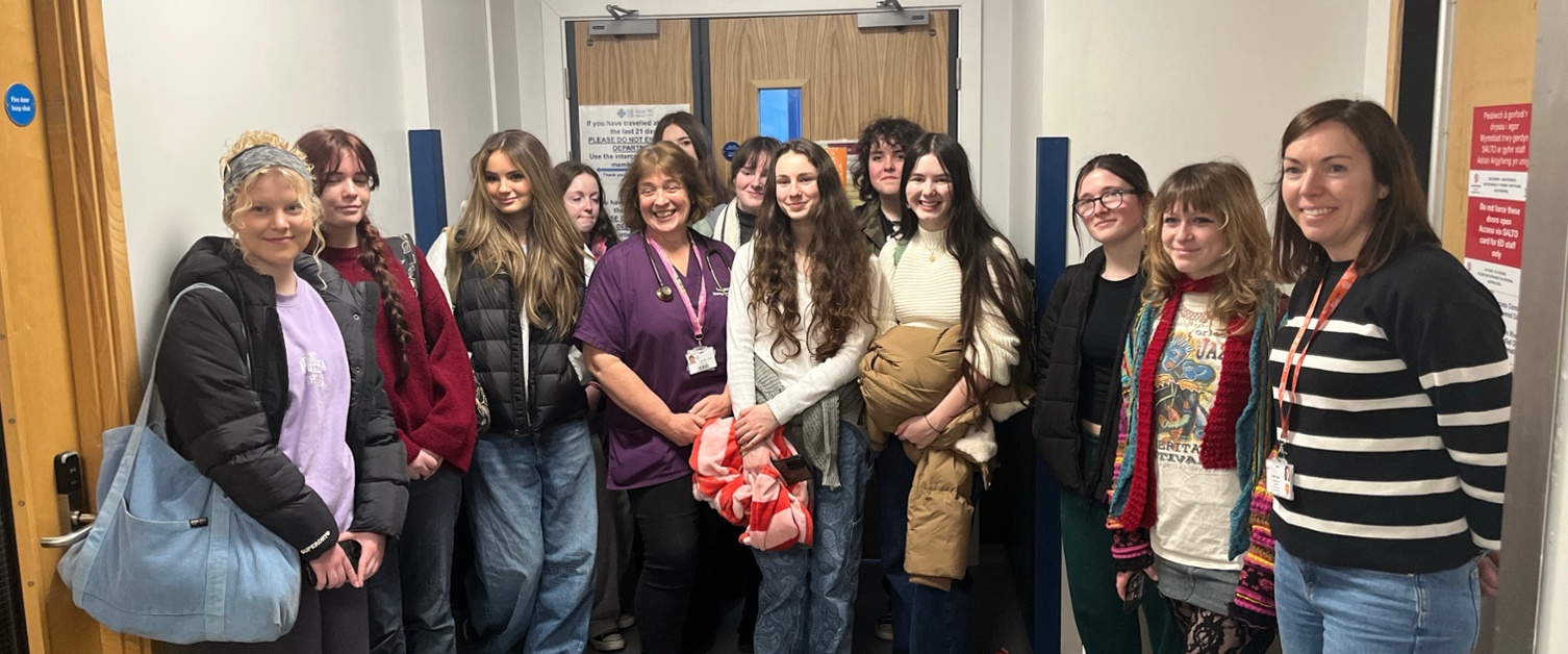 Image shows a group of people standing in a hospital corridor