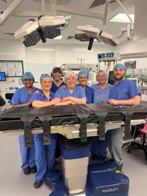 Image shows a group of people stood behind a patient chair in a medical theatre