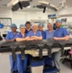 Image shows a group of people stood behind a patient chair in a medical theatre