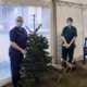 Two staff members pictured with a Christmas tree and wooden reindeer.