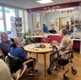 Image shows a woman playing a piano and people sitting at tables