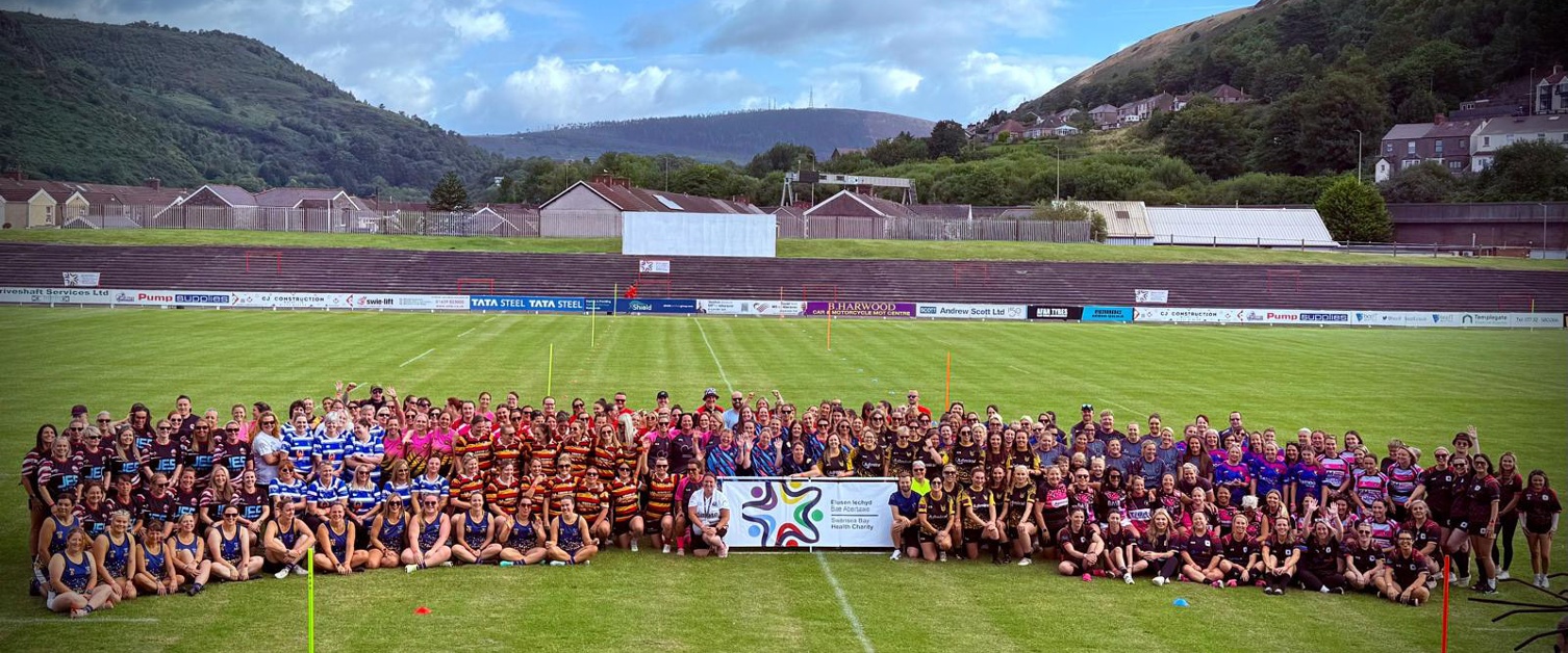 Image shows a large group of women rugby players on a pitch.