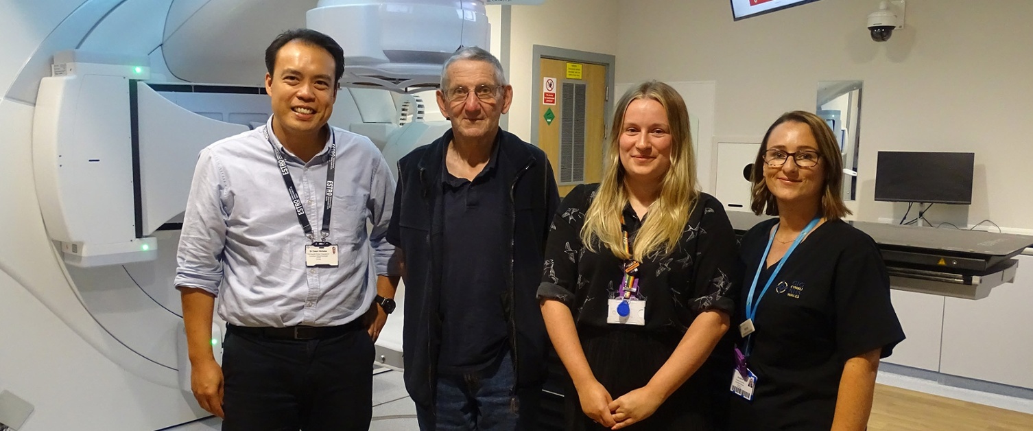 Image shows four people in a radiotherapy room.