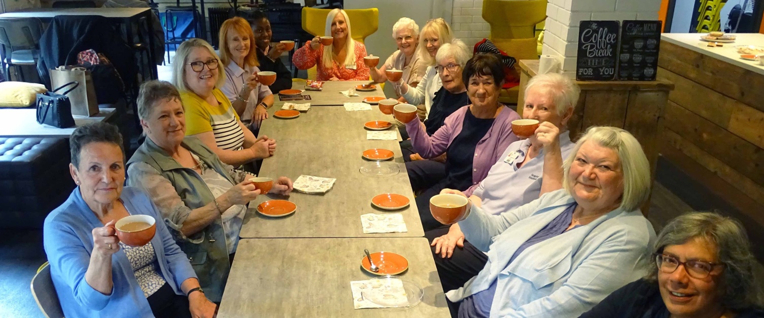 Image shows people seated around a cafe table.