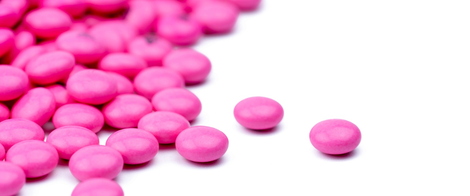 Image shows bright pink amitriptyline tablets on white background.