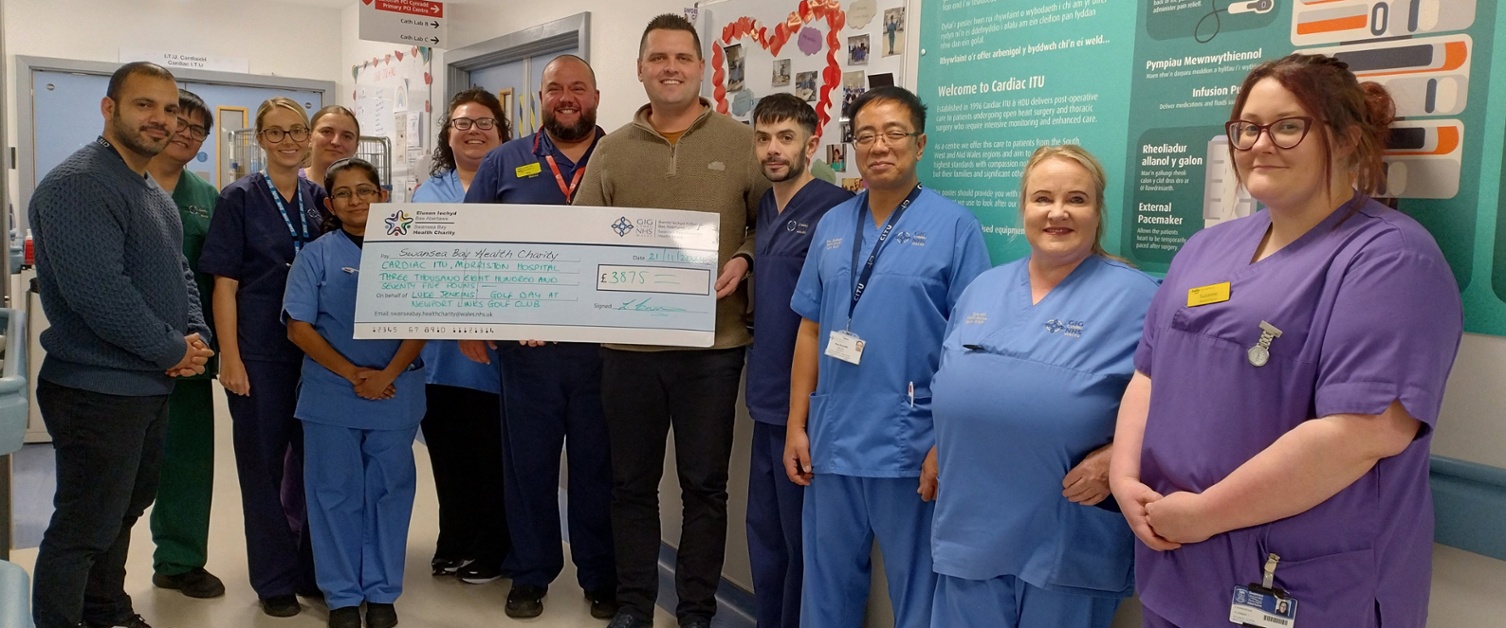 A group of nursing staff standing alongside a man holding a large cheque.