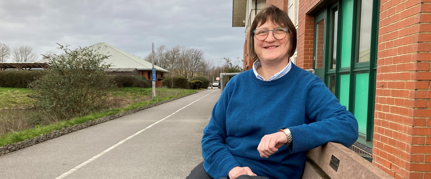 Image shows a woman sitting on a bench