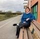 Image shows a woman sitting on a bench
