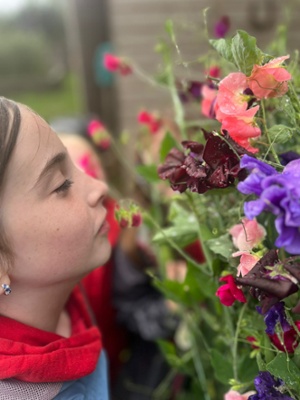 Image shows a child smelling a flower