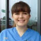 Image shows a nurse smiling into the camera outside a hospital