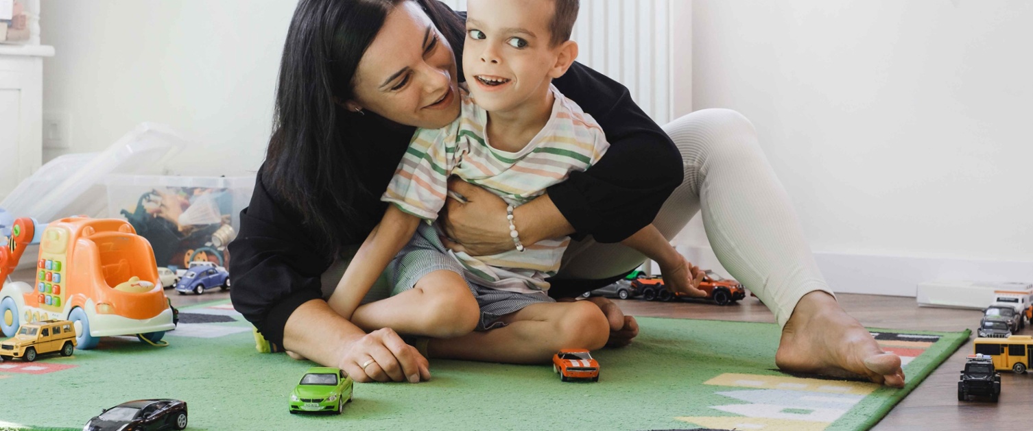 Image shows woman playing with child on the floor.