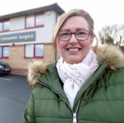 A smiling Anne Robinson standing outside her local GP surgery.