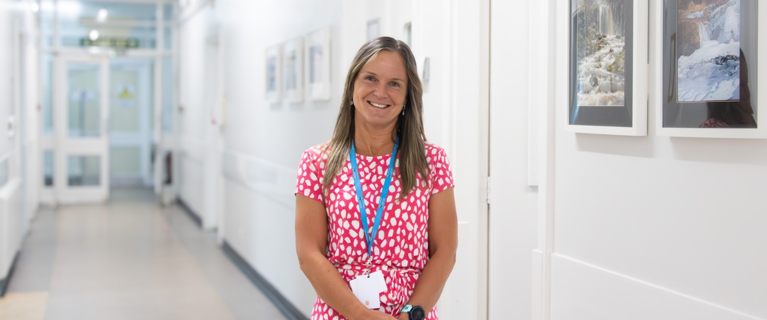 A smiling woman standing in a hospital corridor